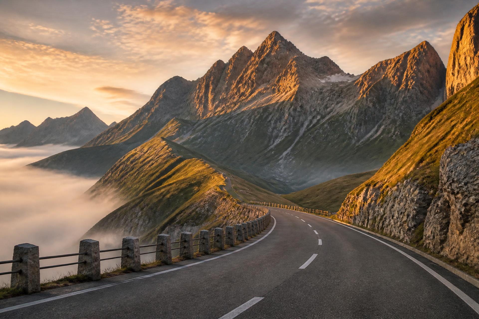 An alpine mountain road curving through peaks at golden hour